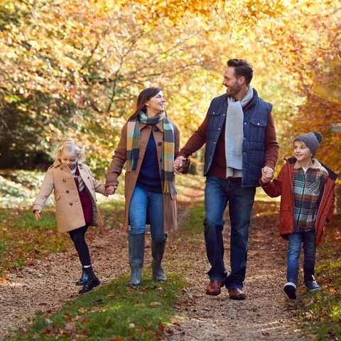 Familie beim Herbstspaziergang auf einem Waldweg