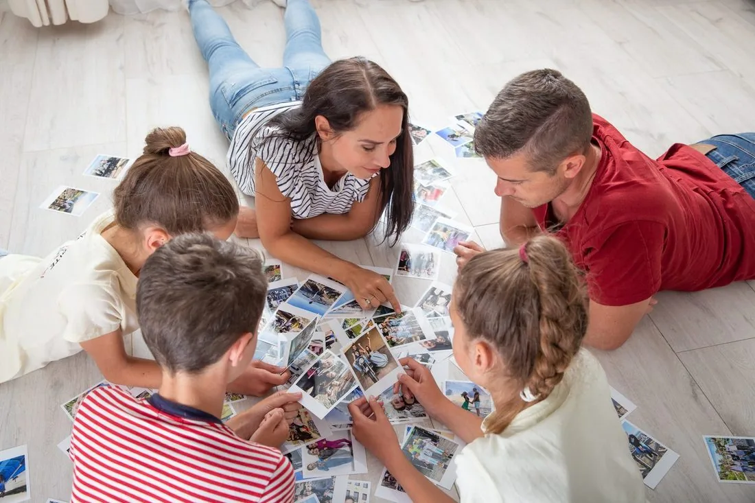 Familie breitet gemeinsam viele gedruckte Fotos aus und entdeckt alte Erinnerungen neu