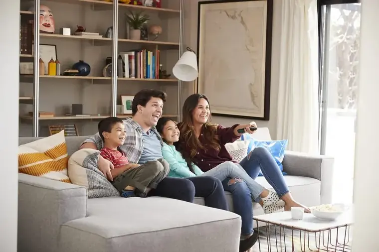 Familie schaut gemeinsam auf dem Sofa ihre digitalisierten VHS-Heimvideos auf dem Fernseher